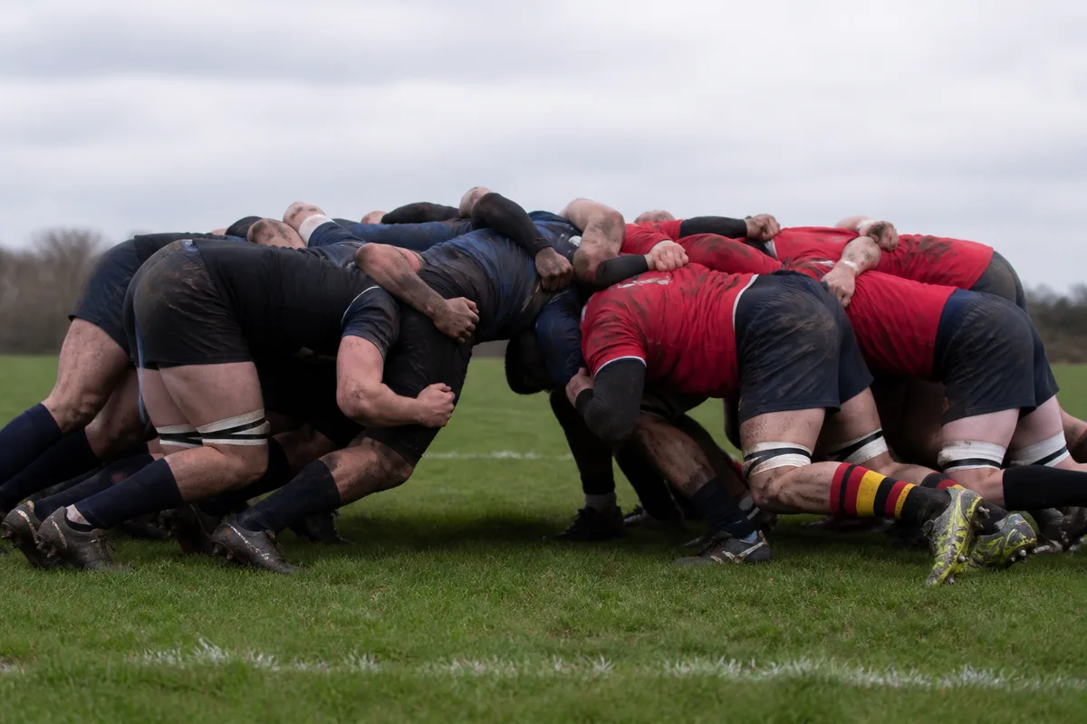 Deux packs de rugby face à face au moment de la liaison, avants penchés en position d&rsquo;engagement sur un terrain herbeux